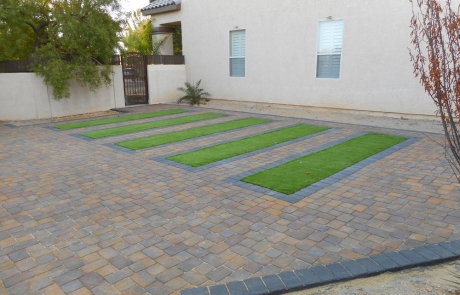 artificial-turf-driveway-border-with-pavers.jpg Artificial turf accents between custom paver driveway strips.