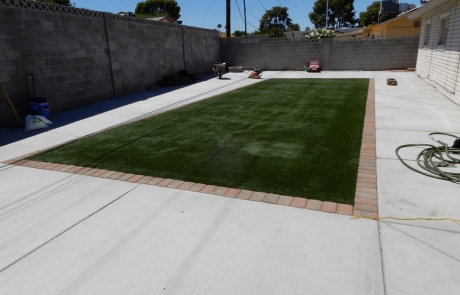 artificial-turf-lawn-with-paver-border.jpg Artificial turf lawn surrounded by concrete with paver brick border.