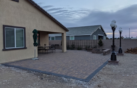 backyard-stone-paver-patio-at-sunset.jpg Wide backyard stone paver patio with outdoor dining and lamp post lighting.