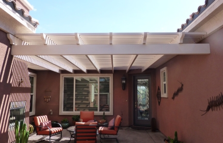 covered-patio-with-white-pergola.jpg Backyard seating area under white pergola with outdoor furniture and paver flooring.