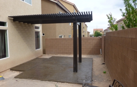 modern-concrete-patio-with-pergola.jpg Modern concrete patio with dark pergola structure in a small backyard.