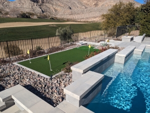 stone-poolside-patio-with-golf-putting-green.jpg Stone patio and poolside area featuring integrated golf putting green.