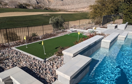 stone-poolside-patio-with-golf-putting-green.jpg Stone patio and poolside area featuring integrated golf putting green.